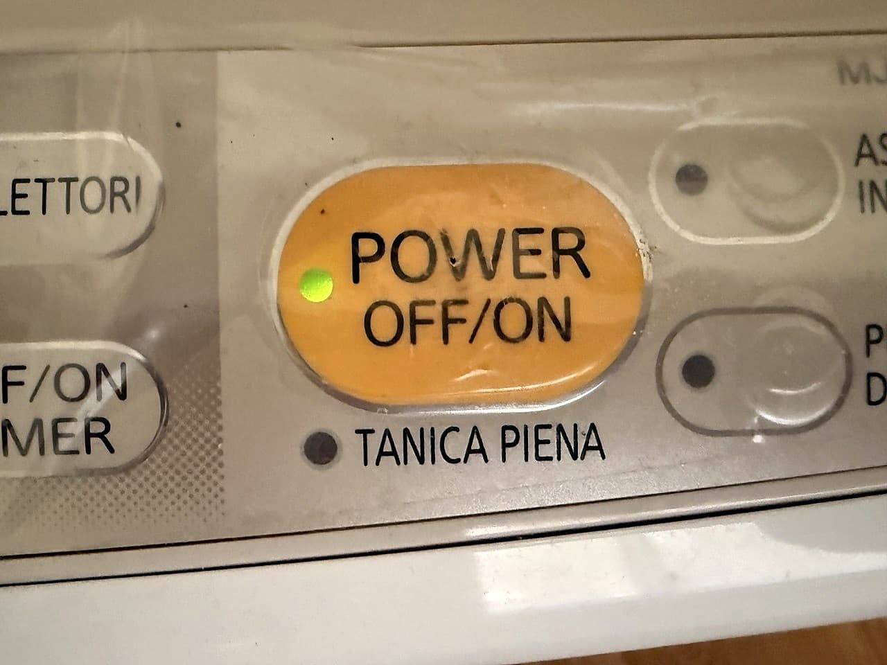 Nahaufnahme des Bedienfelds des Luftentfeuchters mit der gelben POWER OFF/ON-Taste und der kleinen grünen LED, die innen leuchtet · die Anzeige TANK FULL aus