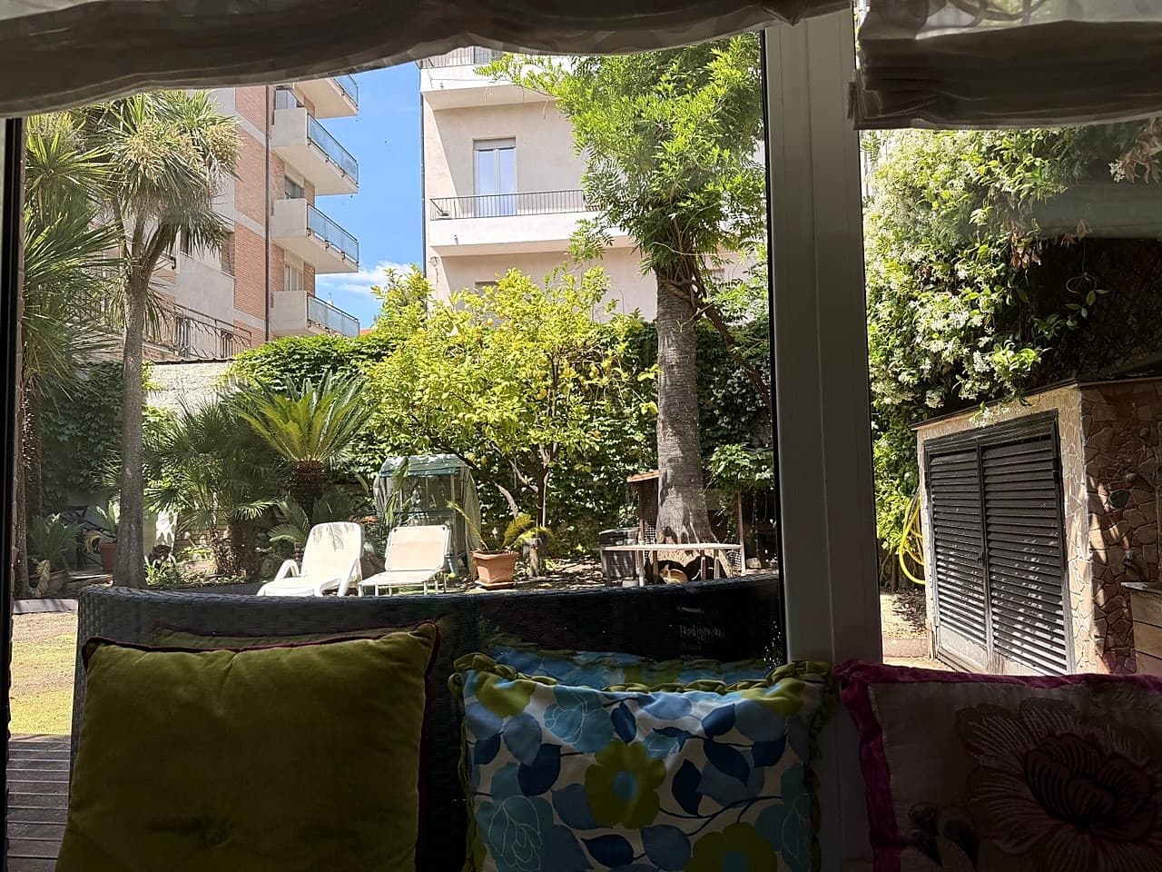 Bodentiefes Fenster zum Garten, mit floralen Kissen auf dem Sofa im Vordergrund