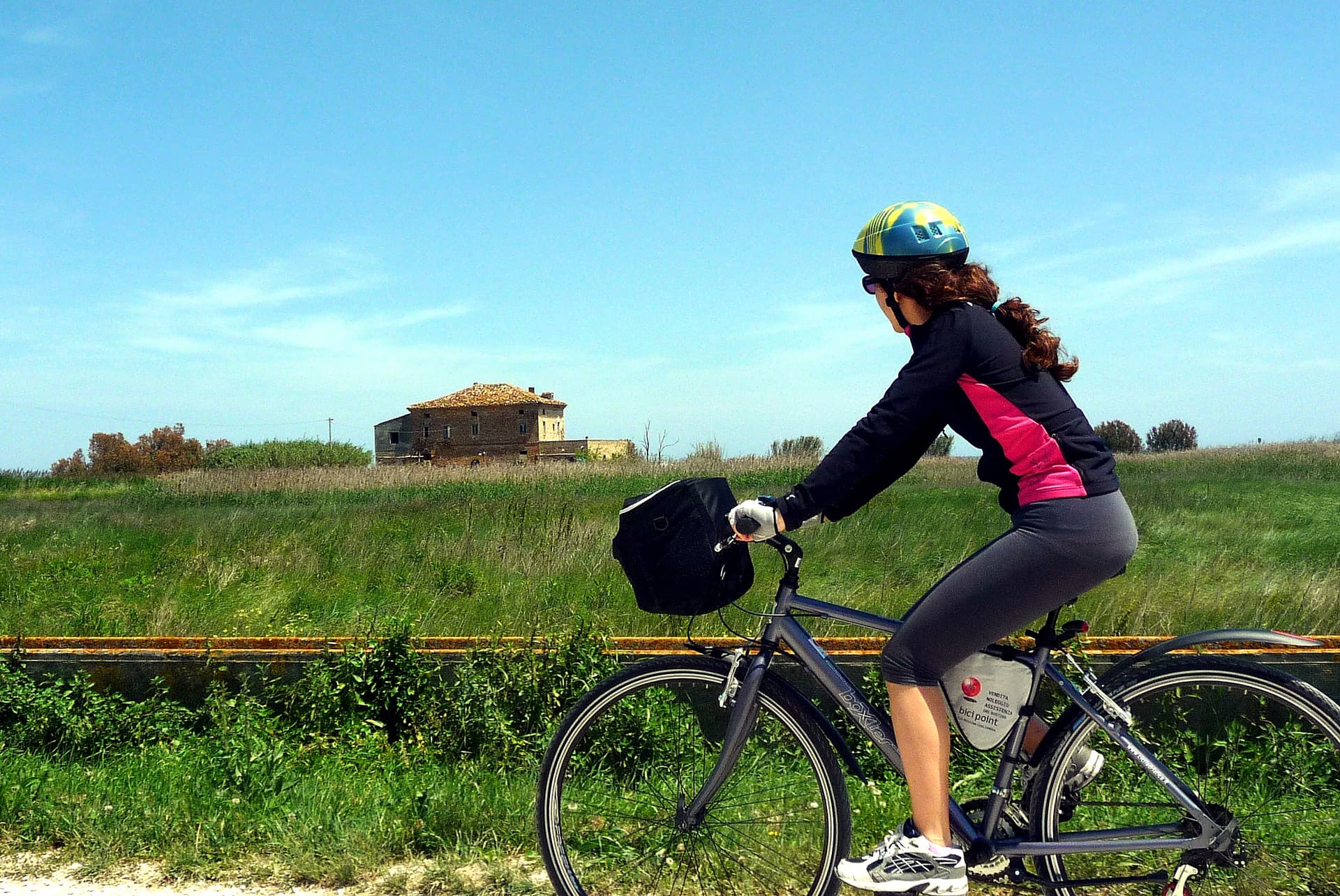 Bici parcheggiata in un sentiero della Riserva Sentina · canneto e vegetazione retrodunale sullo sfondo
