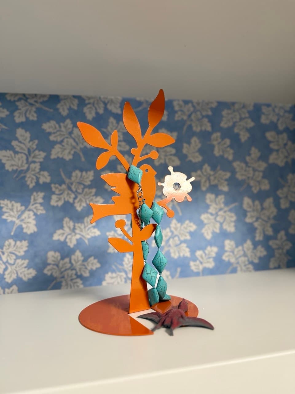 Piccolo albero di metallo arancione con uccellino