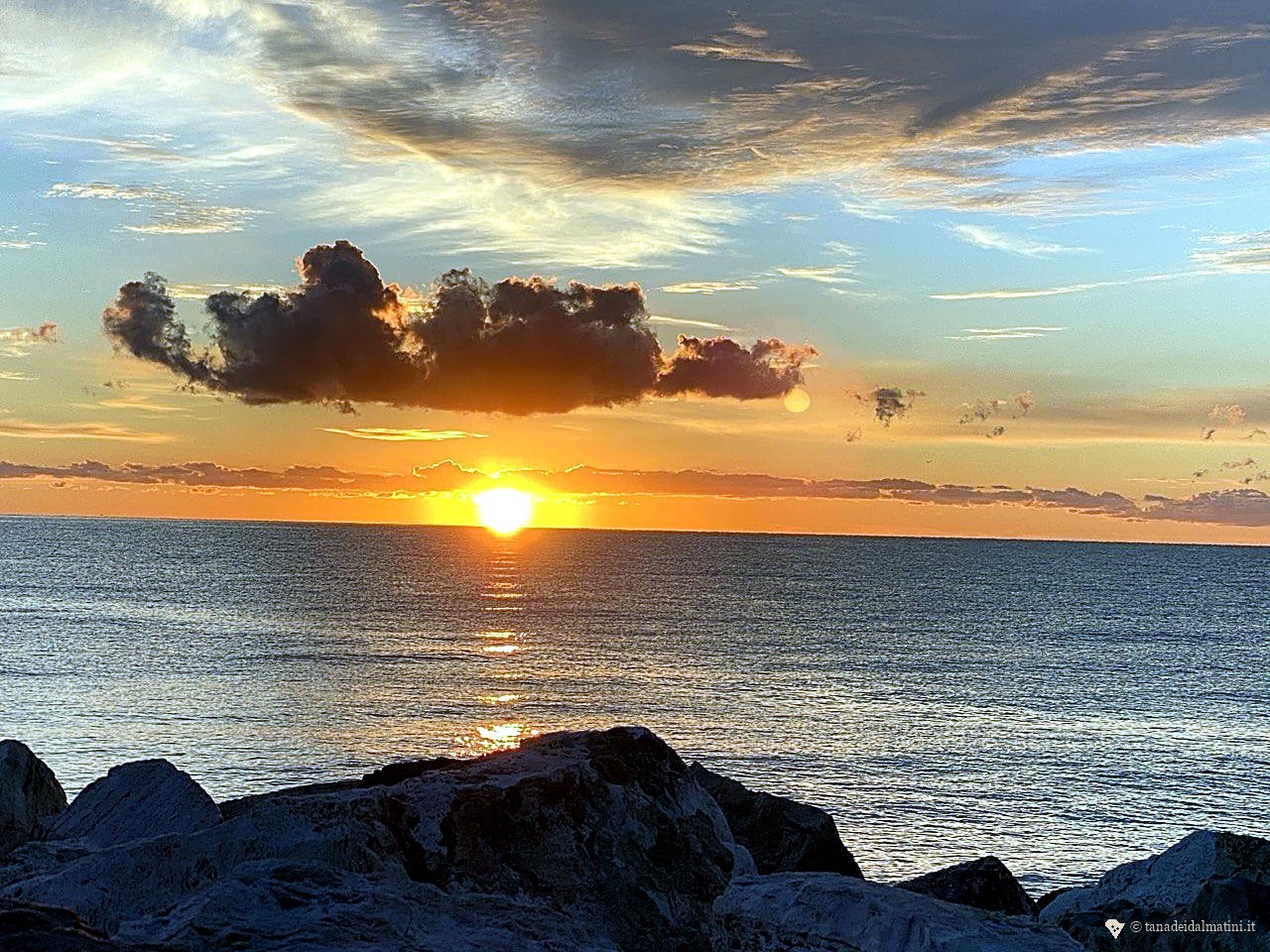 Sole basso sul mare, tonalità arancio del tramonto